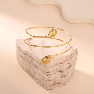 Primo piano dettagliato del bracciale a spirale dorato con estremità a goccia su una pietra