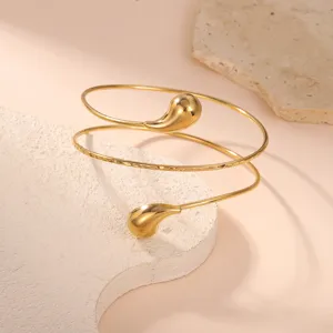 Dettaglio di un bracciale da braccio a spirale dorato con estremità a goccia e trama