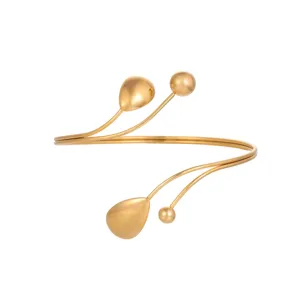 Dettaglio macro di un elegante bracciale geometrico dorato con sfere e gocce decorative