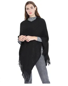 Vue complète d'un élégant poncho en tricot noir avec fils métallisés et franges stylées