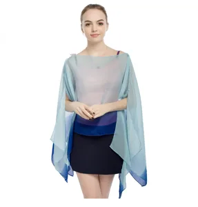 Detalle de un poncho de gasa degradado azul con un elegante cierre de botón de perla lateral.