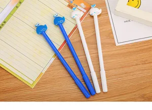 Macro detail of cute cartoon whale-topped gel pens in white and blue on a desk