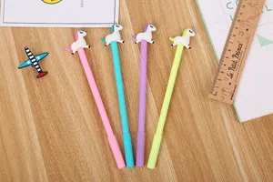 Gros plan de quatre stylos gel licorne colorés avec des figurines de poney sur bois