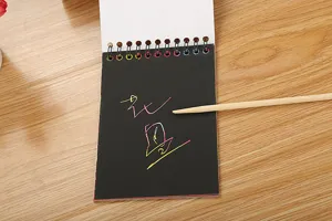 Vista dettagliata di taccuino per scratch art arcobaleno per bambini con stilo in legno