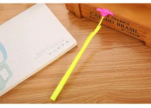 Close-up of a creative yellow gel pen with a pink flower topper on a wooden desk