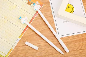 Close-up of cute cartoon whale toppers gel pens on a wooden desk with a notebook background