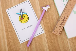 Stylo gel licorne mignon avec figurine sur un bureau en bois avec des accessoires
