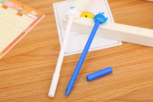 Detailed view of cute cartoon whale-topped gel pens in blue and white colors on a desk