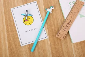 Détail d'un stylo gel licorne cyan mignon sur un bureau en bois avec accessoires