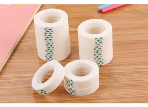 Close-up of multiple rolls of invisible adhesive tape with green arrows on a wooden desk.