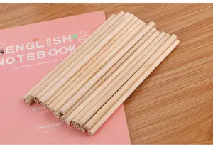 Professional raw natural wood round pencils bundle displayed on a pink notebook background