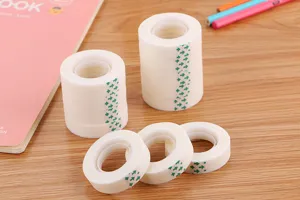 Macro detail view of multiple invisible matte tape rolls on wooden desk with stationery