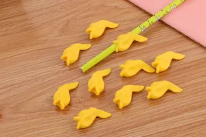 Close-up of yellow fish-shaped soft glue pencil grips for students on wooden desk