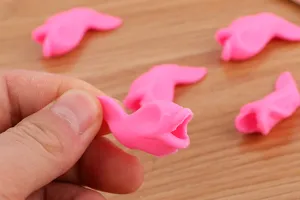 Close-up of a pink fish-shaped silicone pencil grip being held by fingers for detail.