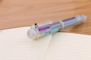 Nahaufnahme eines transparenten 6-Farben-Kugelschreibers auf einem offenen Notizbuch.