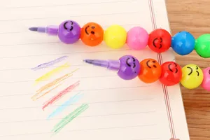 Détail des crayons empilables 7 couleurs avec des visages souriants mignons sur un cahier