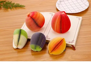 Vista dettagliata di foglietti adesivi 3D a forma di frutta su una scrivania di legno.