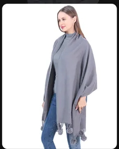 Eleganter grauer Strickschal mit Bommeln, präsentiert von einem Model im Studio.