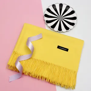 Nahaufnahme eines leuchtend gelben Schals mit eleganten Fransen und Cashmere-Etikett.
