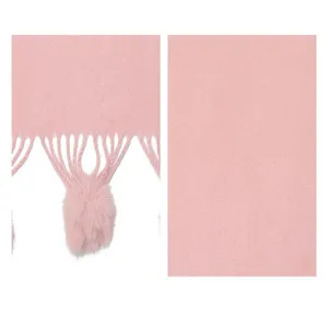 Detailansicht der weichen rosa Strickschal-Textur und des flauschigen Fellbommel-Dekors