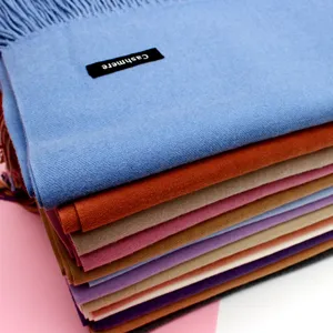 Nahaufnahme von gestapelten bunten Strickschals mit Fransen und Cashmere-Etikett-Tags
