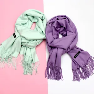 Nahaufnahme von weichen Winterschals in Minzgrün und Lila mit eleganten Fransen