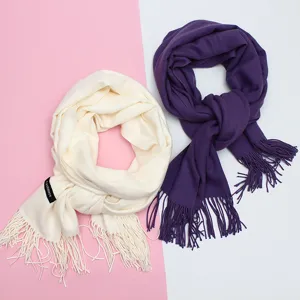 Detailansicht von unifarbenen, warmen Strickschals mit Fransen in den Farben Creme und Violett.