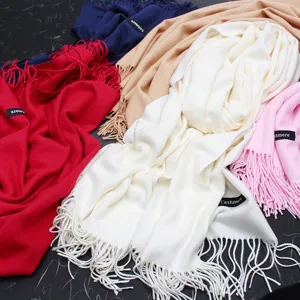 Detailaufnahme von weichen Strickschals in verschiedenen Farben mit Quasten und Etiketten
