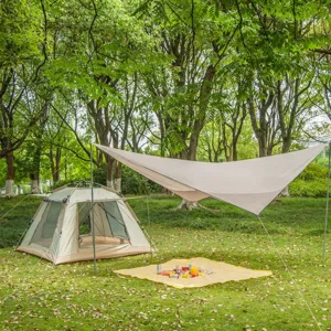 Détail de scène de camping en plein air avec bâche et tente beige résistantes.