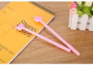 Vue détaillée de stylos gel mignons en forme de flamant rose sur un carnet jaune