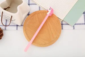 Stylo gel rose mignon avec un capuchon licorne 3D sur un support décoratif en bois.