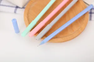 Vue macro montrant les pointes fines des stylos gel pastel colorés sur un plateau en bois