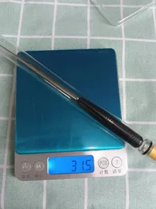 Stainless steel fishing hook remover tool detail view showing product weight on scale.