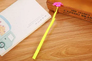 Creative yellow flower-shaped gel pen with pink petals on a wooden desk detail view