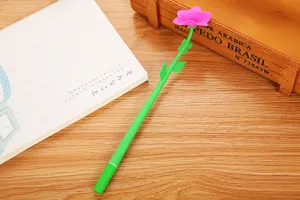 Macro view of a creative pink flower gel pen resting on a wooden desk with a notebook