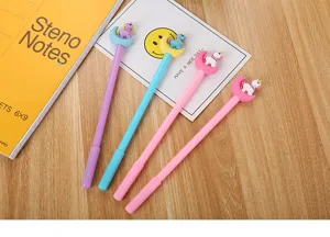 Gros plan de stylos gel licorne et lune colorés sur un bureau en bois avec carnet.