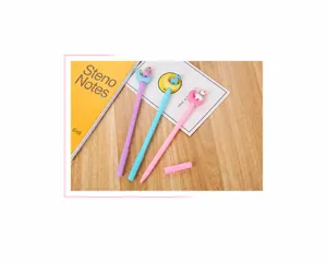 Gros plan de stylos gel pastel avec de mignons embouts lune et licorne sur un bureau en bois.