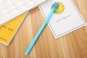 Detailansicht eines niedlichen blauen Cartoon Monster Gelschreibers auf einem Holztisch