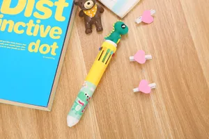 Gros plan détaillé d'un stylo à bille 10 couleurs avec un bouchon de dinosaure vert