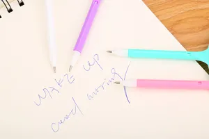 Macro shot of colorful pastel ballpoint pens on a white notebook with blue handwriting text