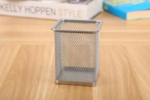 Primer plano de un portalápices rectangular de malla metálica plateada en un escritorio