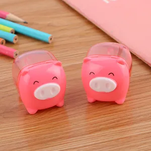 Cute pink pig-shaped pencil sharpeners for students on a wooden desk with colored pencils