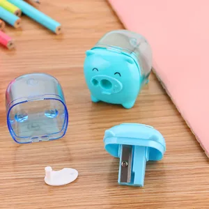 Cute blue pig-shaped mini pencil sharpener for student stationery shown on a wooden desk