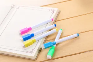 Close-up of colorful whiteboard markers with built-in eraser caps on a notebook