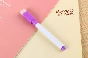 Detail of a purple whiteboard marker with integrated eraser cap on a notebook.