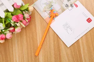 Vue détaillée d'un stylo gel licorne orange mignon sur un bureau en bois avec des fleurs