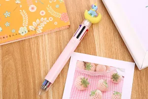 Detail view of pink multi-color ballpoint pen with cute unicorn topper on a wooden desk