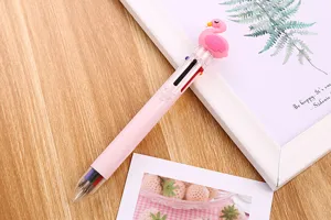 Close-up of a cute flamingo 6-color ballpoint pen on a wooden desk with lifestyle props