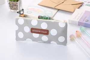 Close-up of a gray polka dot Oxford cloth pencil case with Geometry Valley logo patch.