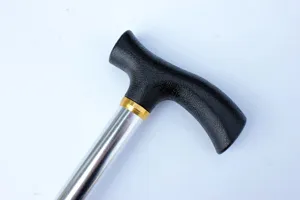 Dettaglio del bastone da passeggio per anziani con impugnatura ergonomica a T e stelo in metallo.